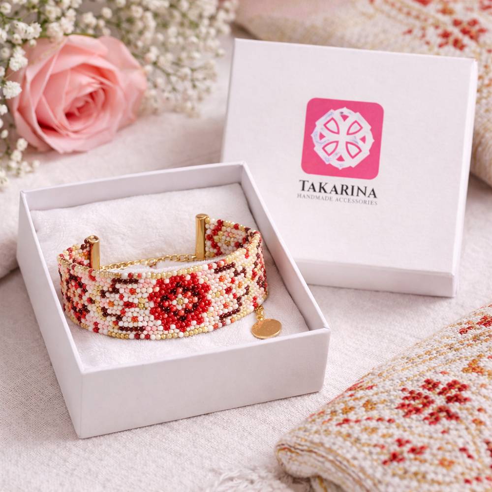 دستبند منجوق‌بافت دست‌ساز با طرح گل‌های قرمز و سفید برند تک آرینا داخل جعبه